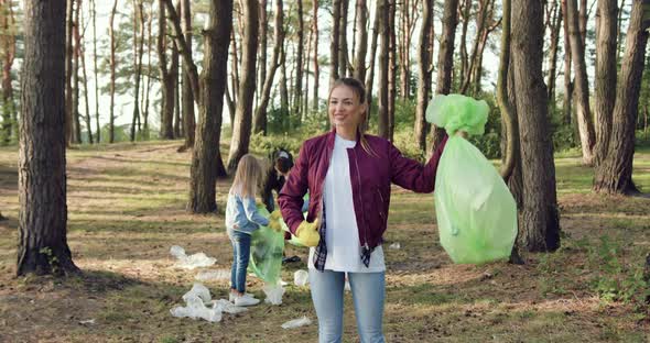 Woman Posing on Camera with Collected Rubbish Near Another Friends-Activists of Nature Lovers