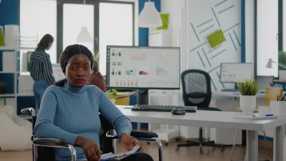 Black Woman with Disabilities Looking at Camera Sitting in Business Office