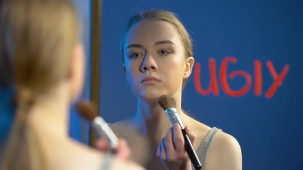 Sad School Teenager Applying Face Powder Looking Mirror, Word Ugly Written Glass