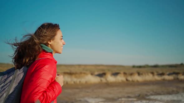 Slow Motion Portrait of Happy Confident and Joyful Young Woman Hiker in Red Jacket Walking on Salty