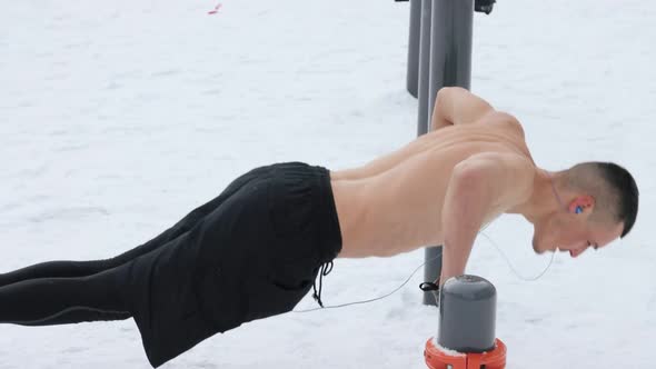 Muscular man training topless on sports field in winter