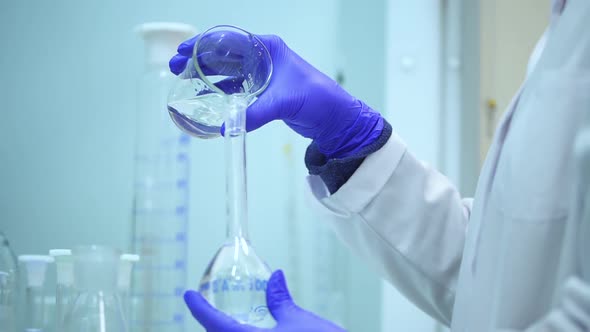 Scientist Mixing Two Clear Transparent Liquids in a Beaker Spbd