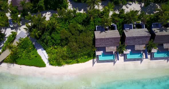 Wide angle aerial travel shot of a white sandy paradise beach and aqua turquoise water background in