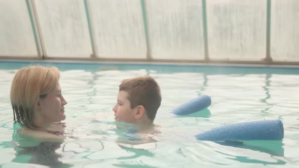 Mother teaching seven-year-old son to swim in the swimming pool.