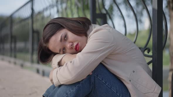 Side View Portrait of Depressed Caucasian Young Beautiful Woman with Dwarfism Hugging Knees Looking