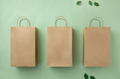 Three cardboard brown paper bags on a green eco background and green leaves. - PhotoDune Item for Sale