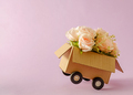 Cardboard box delivery container with truck wheels and bouquet of pink roses. - PhotoDune Item for Sale