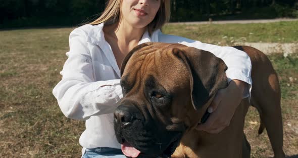 Happy Young Female Cheerfully Playing Sitting with Dog in the Lawn