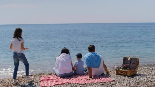 Family with boy and girl sitting with back forward at beach on sunny summer day.