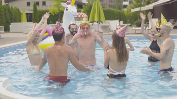 Group of Cheerful Young People Having Fun in Water Pool. Portrait of Happy Redhead Caucasian Man