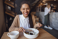 Young woman smiling toothy smile to camera while snacking at a food and drink establishment - PhotoDune Item for Sale
