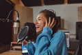 Woman presenter talks into microphone, records audio podcast in professional recording studio - PhotoDune Item for Sale