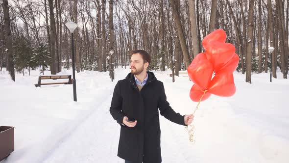 Romantic Man with Red Balloons Is Waiting for a Date with His Beloved Woman on a Winter Day in an