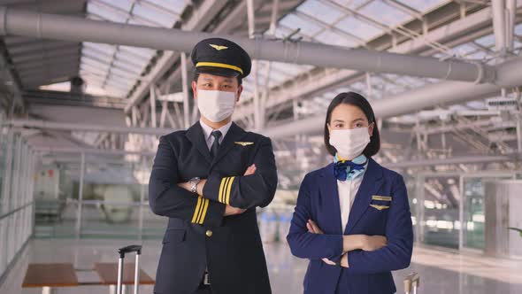 Airliner pilot and air hostess people wearing face mask walking in airport terminal to the airplane.