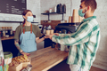 Woman barista in medical mask giving coffee to customer in cafe - PhotoDune Item for Sale
