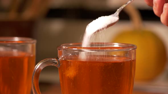 Adding a teaspoon of crystal white sugar into a hot steaming tea