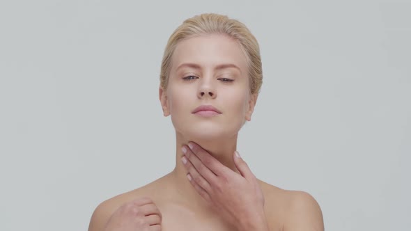 Studio portrait of young, beautiful and natural blond woman applying skin care cream. F