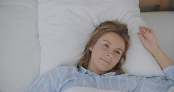 Close Up Face of Young Caucasian Woman Lying and Stretching on Bed After Waking Up Early in the