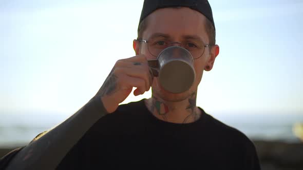 Stylish Tattooed Guy in Glasses Happily Drinking Coffee Made By Himself Smiling to Camera Slomo