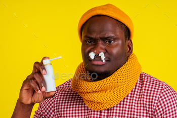 shirt with knitted scarf and hat bad unwell with fever heat and chills in studio yellow background.Spray for the throat flu and virus concept.