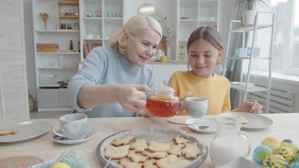 Grandma Pouring Tea for Granddaughter on Easter Day