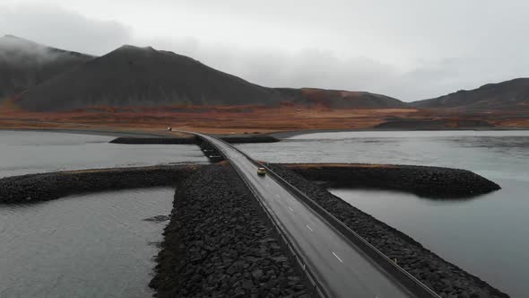 Drone Aerial View of Car on River Overpass in Scenic Humid Landscape of Iceland.