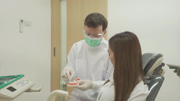 A caucasian dentist man, people showing how to use dental floss with typodont teeth model