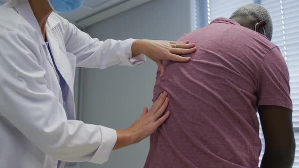 Diverse female orthopedic doctor examining male patient in face masks