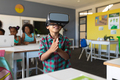 Smiling african american elementary schoolboy wearing vr glasses while standing in classroom - PhotoDune Item for Sale