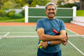 Portrait of biracial happy senior man with arms crossed holding balls and racket at tennis court - PhotoDune Item for Sale