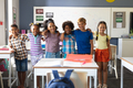Portrait of smiling multiracial elementary school students standing with arm around in classroom - PhotoDune Item for Sale