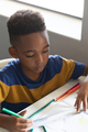 High angle view of african american elementary schoolboy drawing line on book at desk in classroom - PhotoDune Item for Sale