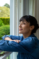 Smiling thoughtful caucasian young woman with arms crossed looking through window - PhotoDune Item for Sale