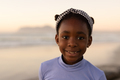 Portrait of smiling african american cute girl wearing headband against sea and clear sky at sunset - PhotoDune Item for Sale