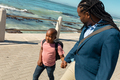 African american father looking while holding hand of son walking on promenade during sunny day - PhotoDune Item for Sale