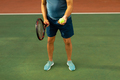 Low section of biracial senior man holding tennis racket and ball while standing at tennis court - PhotoDune Item for Sale