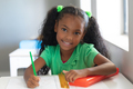 Portrait of smiling african american elementary schoolgirl with ponytails sitting at desk in class - PhotoDune Item for Sale