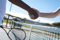 Cropped hands of biracial female tennis players doing handshake over net at court on sunny day - PhotoDune Item for Sale
