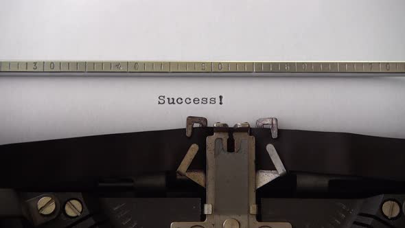 Typing word Success ! on retro typewriter. Close up.