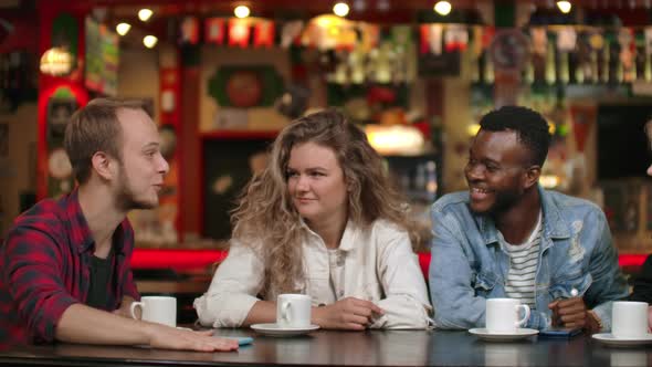 A Man in a Shirt Tells a Story to Friends Two Girls and an African American are Listening and