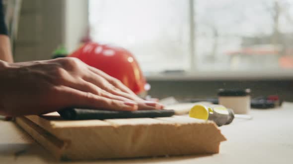 Woman Builder Sanding Wooden Board with Sandpaper