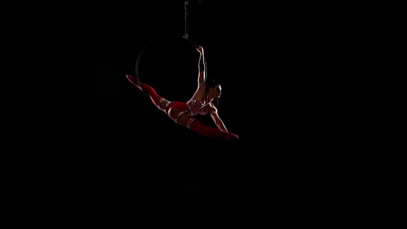 Girl Hanging in Ring for Aerial Acrobatics. Black Background. Slow Motion