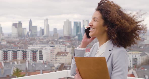 Businesswoman talking on the phone standing on windy roof top terrace