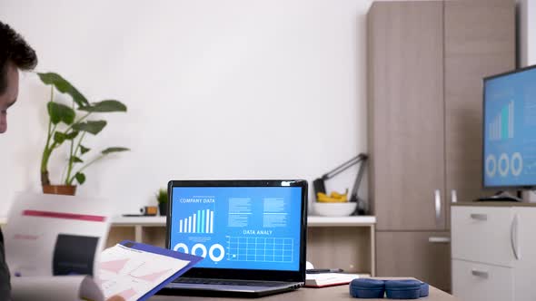 Man in His Living Room Checking Company Data on Animated Charts