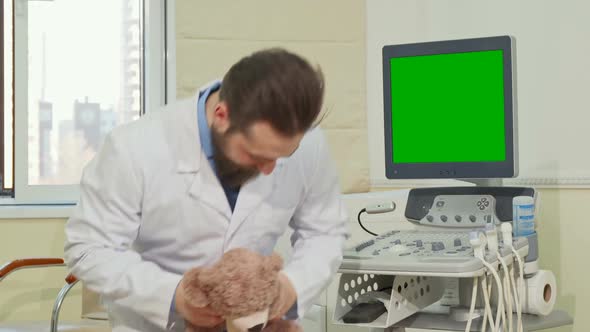 Pediatrician Holding Teddy Bear Ultrasound Scanner with Green Screen on the Back