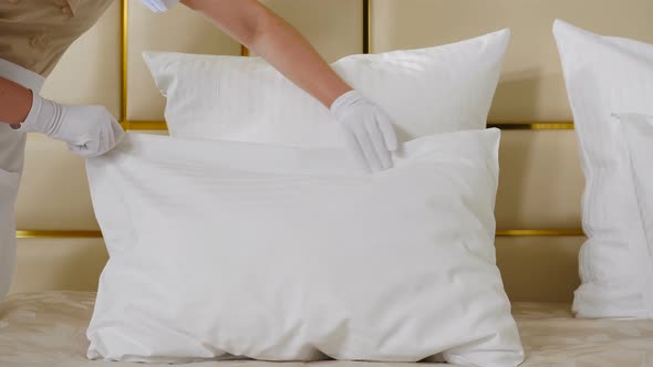 Hotel Cleaning Concept. Close-up View of Young Pretty Maid in Uniform Making Bed in Room Touching