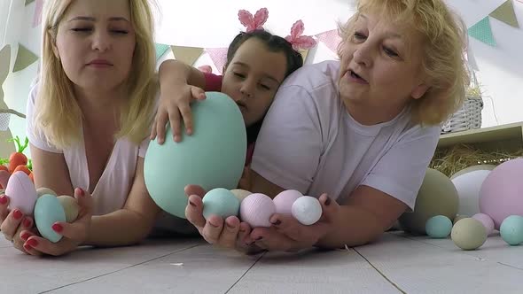 Pretty Little Girl Giving Decorated Eggs and Greeting Cards to Mother and Grandmother at Easter