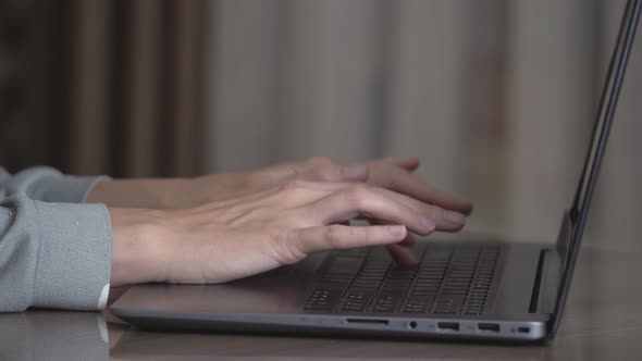 Housewife female hands are typing on a laptop close-up