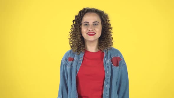 Smiling Girl Makes Sign Ok Over Yellow Background, Slow Motion