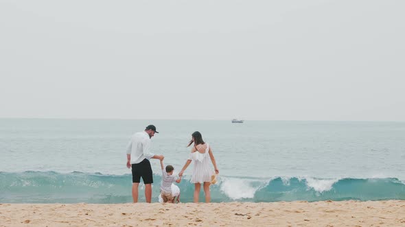 Happy Family, Young Father and Mother Lift Their Little Children Holding Hands Together Smiling on